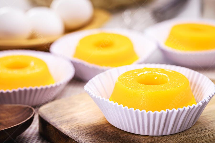 Quindins amarelos em forminhas brancas com ovos e ingredientes
