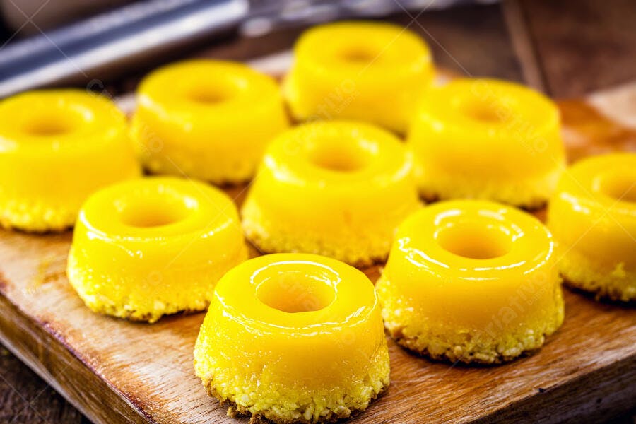 Pudins de quindim amarelos sobre tábua rústica de madeira doce tradicional
