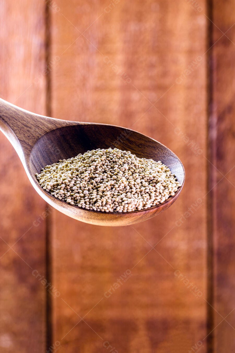 Colher de pau com sementes de quinoa sobre fundo de madeira rústica