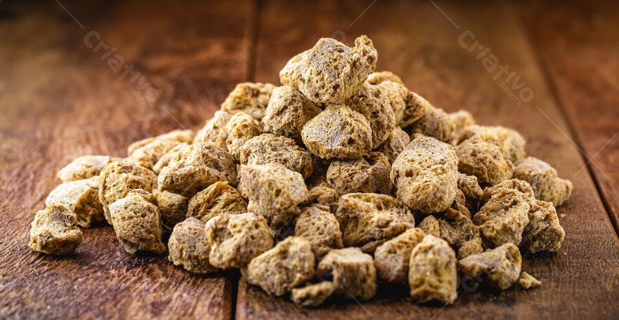 Proteína de soja texturizada em pedaços marrons sobre mesa rústica de madeira