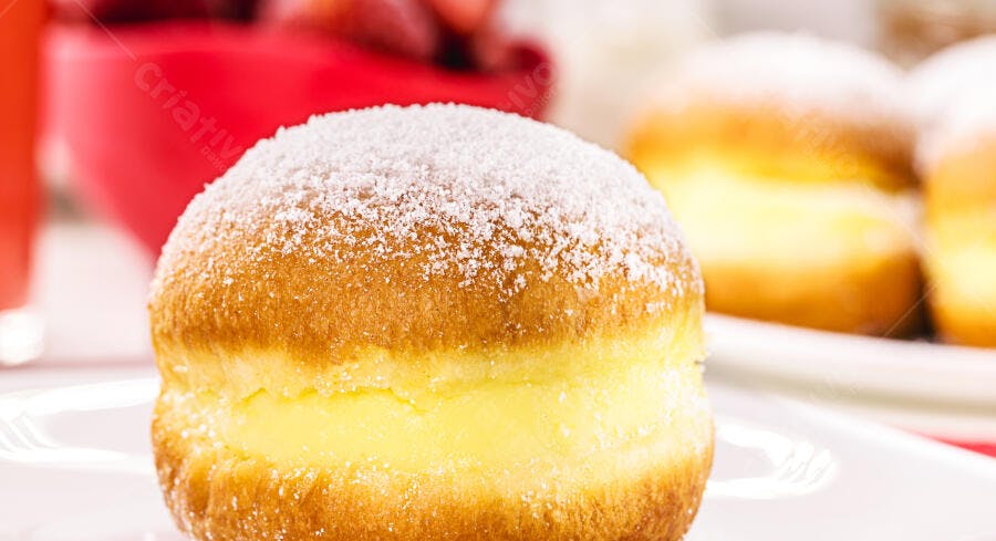 Sonho recheado com creme polvilhado com açúcar em prato branco