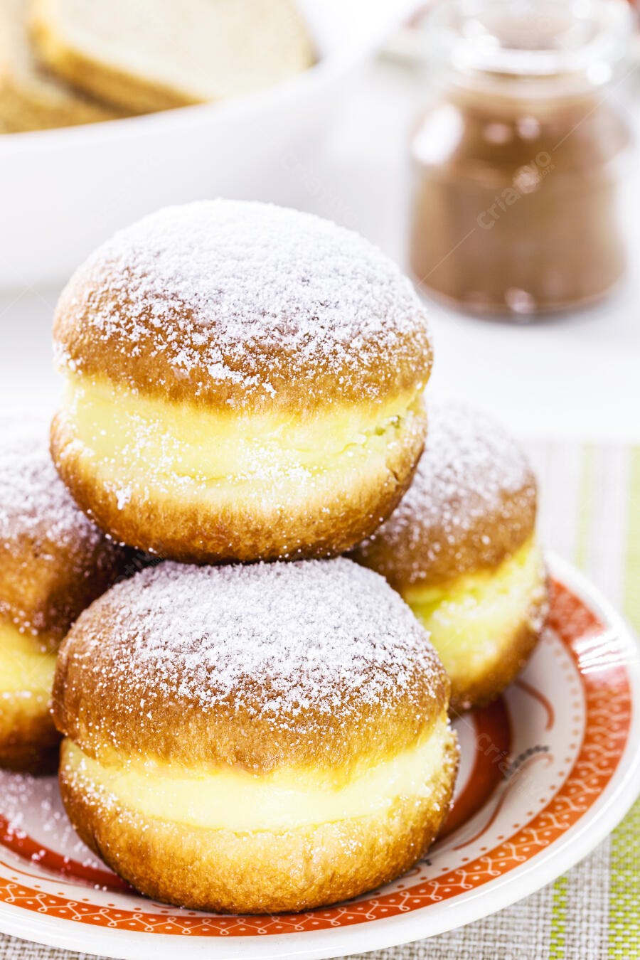 Sonhos de padaria recheados com creme e açúcar em prato decorado