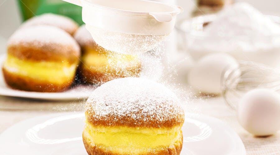 Sonho doce polvilhado com açúcar de confeiteiro e recheio cremoso de baunilha