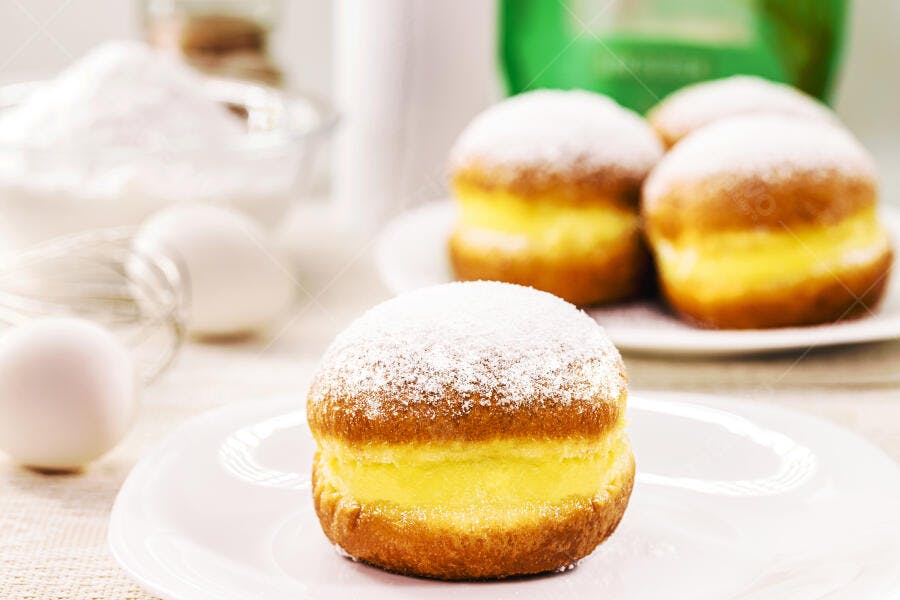 Sonho brasileiro recheado com creme e açúcar de confeiteiro na bancada da cozinha