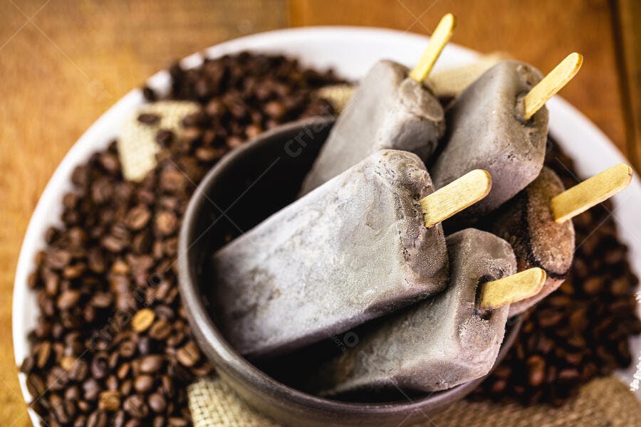 Picolés de café cremosos em tigela escura com grãos torrados ao fundo