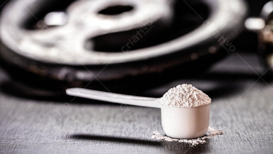 Scoop de proteína em pó branco em academia escura