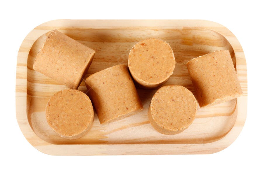 Paçoca doce de amendoim tradicional em bandeja de madeira clara fundo branco