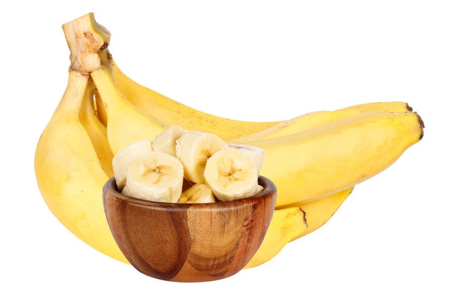Bananas amarelas maduras e rodelas frescas em tigela de madeira