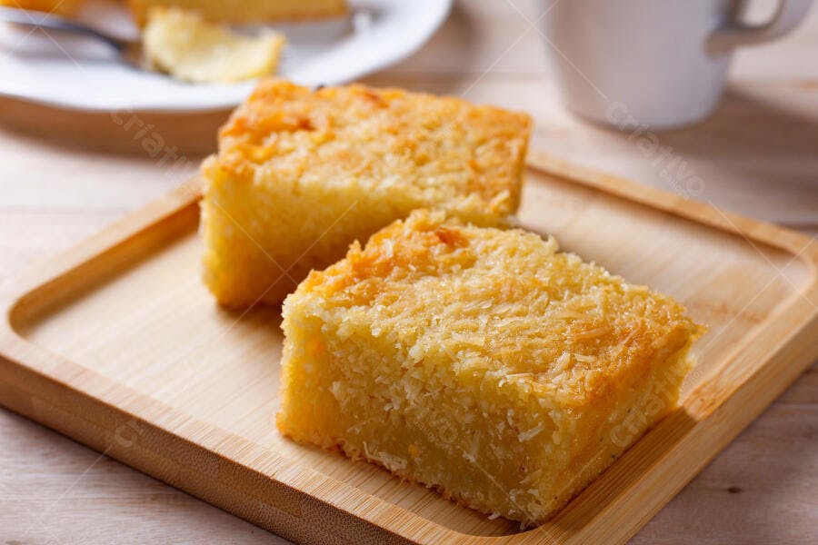 Bolo de milho cremoso com coco ralado em tábua de madeira