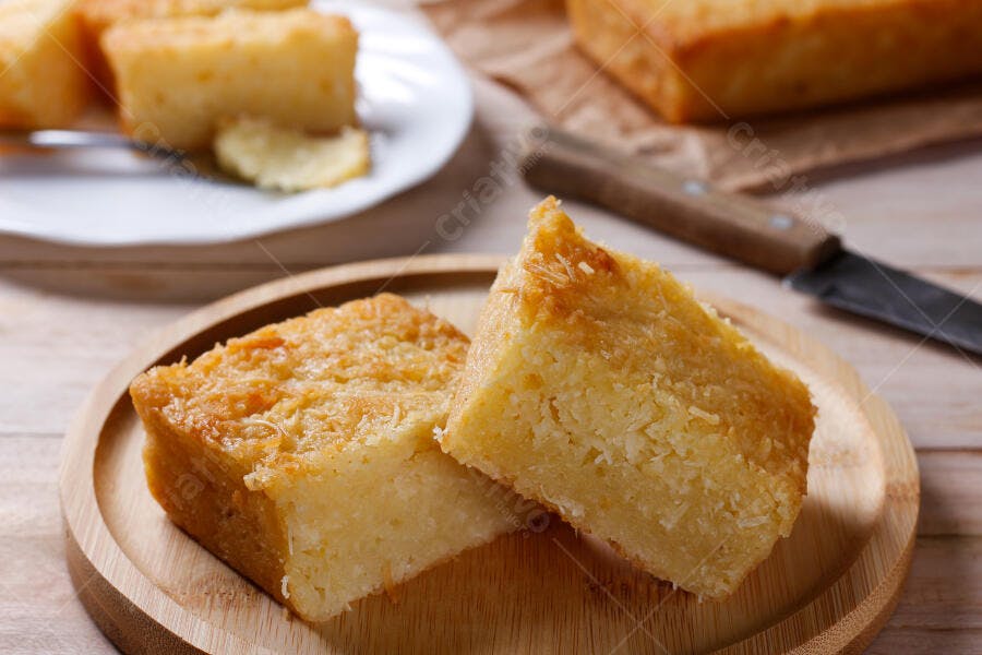 Bolo de coco cremoso fatiado sobre tábua de madeira rústica