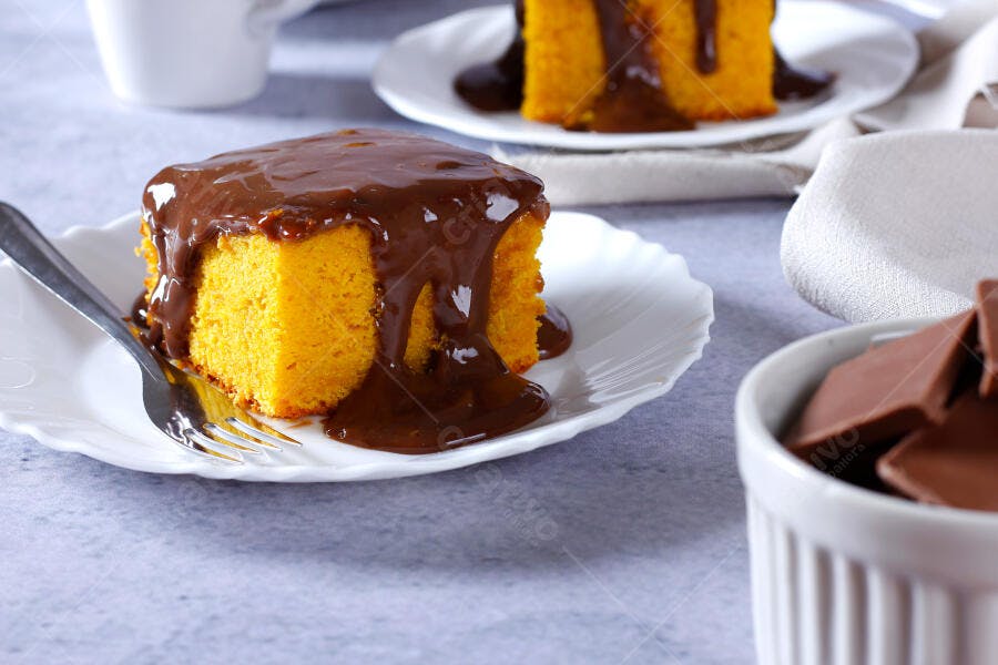 Bolo de cenoura com cobertura de chocolate em prato branco com garfo