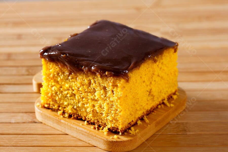 Fatia de bolo de cenoura com cobertura de chocolate em tábua de madeira