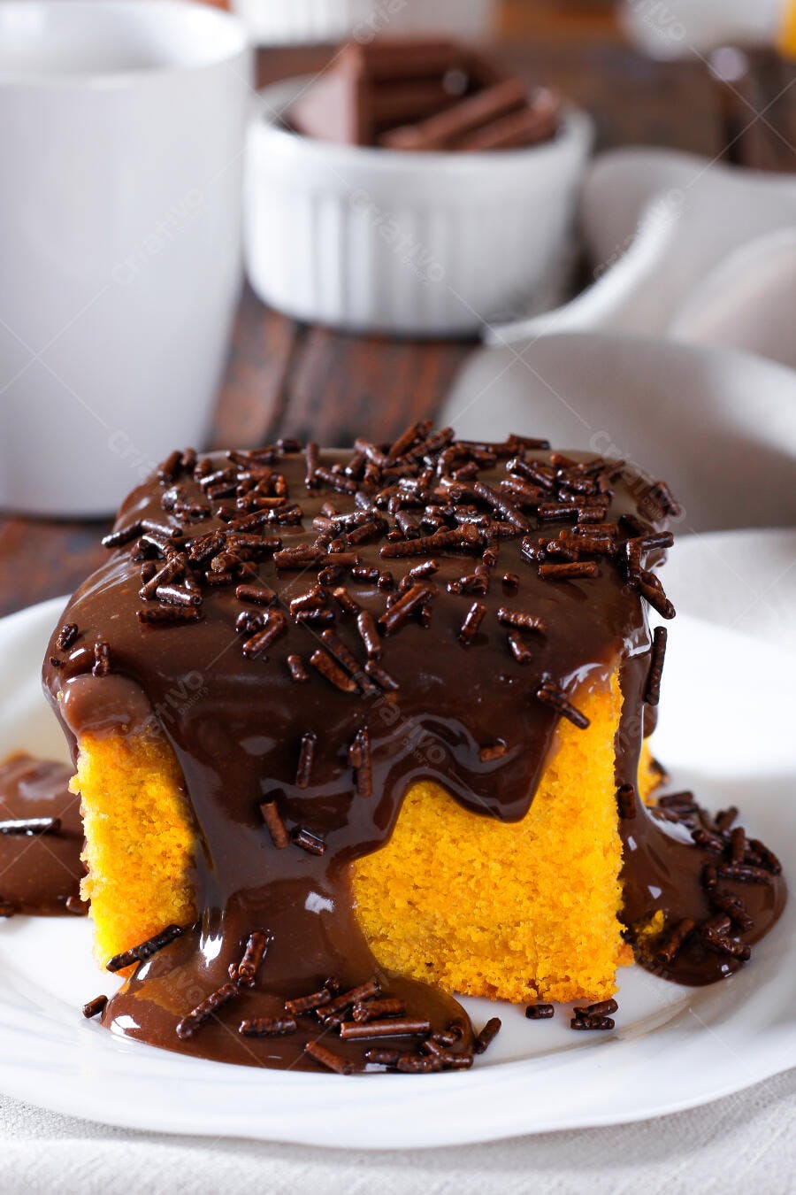 Bolo de cenoura com calda de chocolate e granulado em prato branco