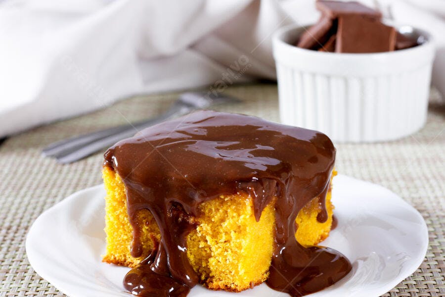 Fatia de bolo de milho fofo com calda de chocolate escorrendo
