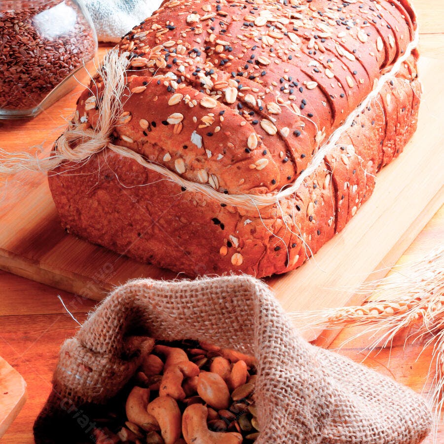 Pão multigrain fatiado com sementes e grãos em tábua de madeira rústica