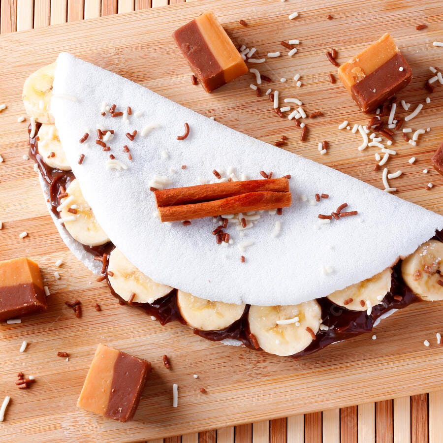 Tapioca doce com banana chocolate e canela em prancha de madeira