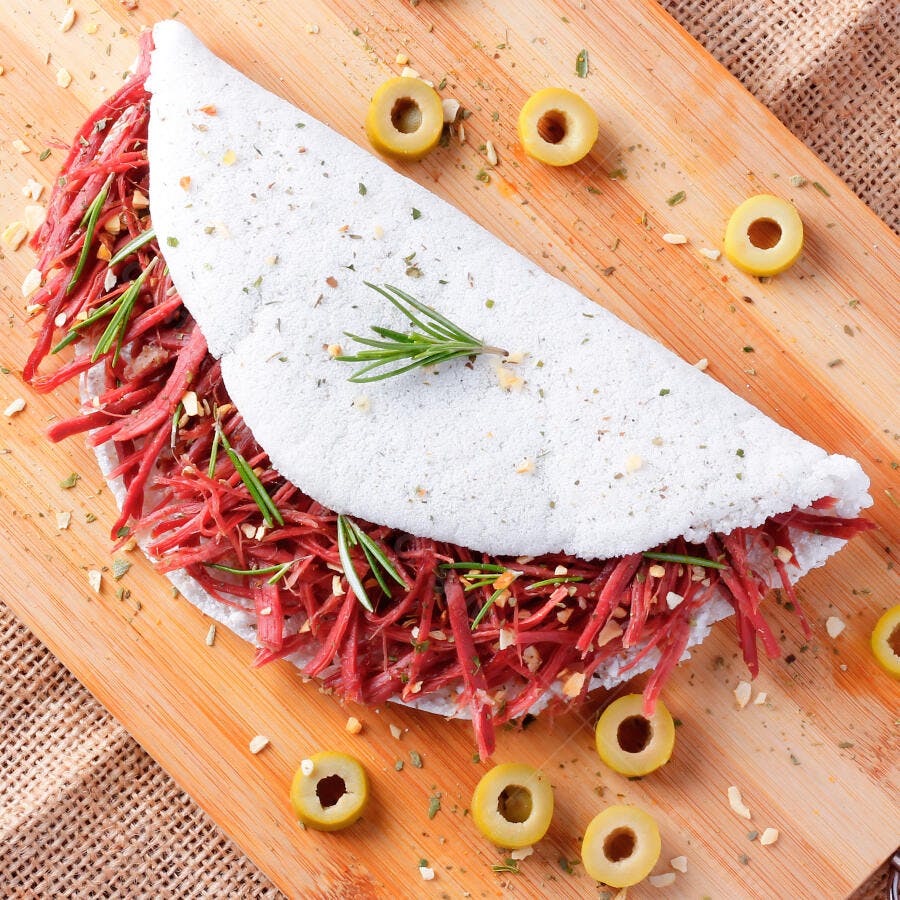 Tapioca brasileira com carne seca desfiada e alecrim em tábua de madeira