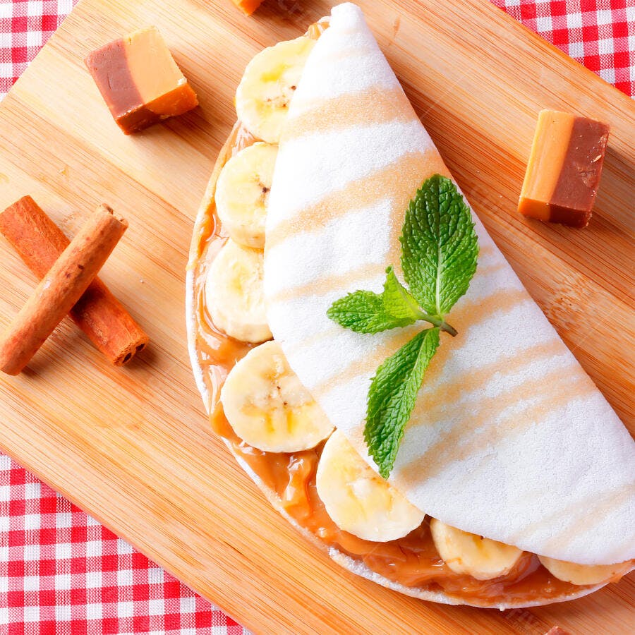 Tapioca brasileira com banana doce de leite e hortelã em tábua de madeira