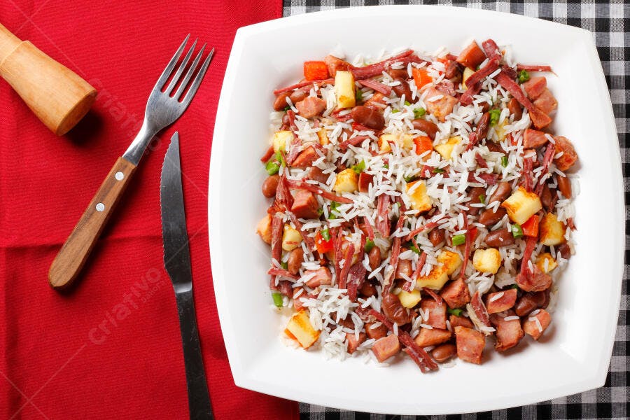 Prato de arroz feijão e carne com queijo sobre toalha de mesa festiva