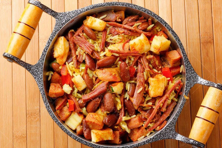 Arroz colorido com carne desfiada feijão e cubos fritos em panela rústica