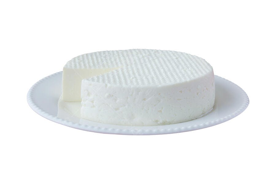 Queijo fresco branco redondo fatiado em prato branco fundo isolado