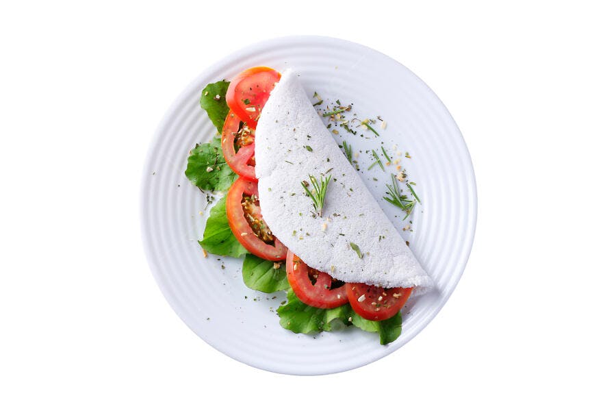 Tapioca recheada com tomate alface e ervas frescas em prato branco isolado