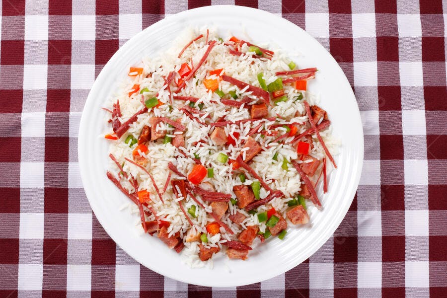 Prato de arroz colorido com carne seca e legumes em toalha xadrez