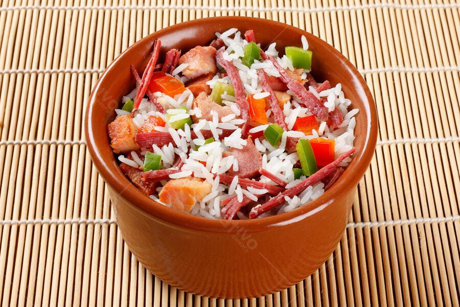 Tigela de arroz com carne pimentões e salame sobre esteira de bambu