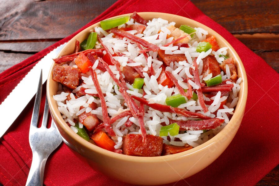 Prato de arroz com carne seca linguiça pimentões coloridos em tigela rústica