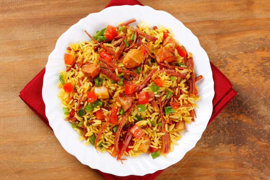 Prato de arroz com carne desfiada e vegetais em mesa rústica de madeira