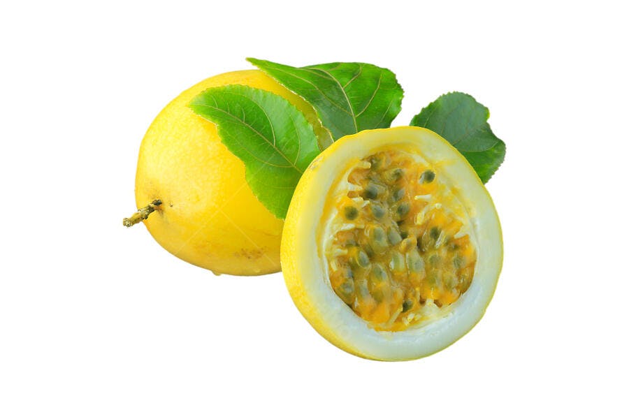 Maracujá amarelo cortado ao meio com folhas verdes frescas em fundo branco