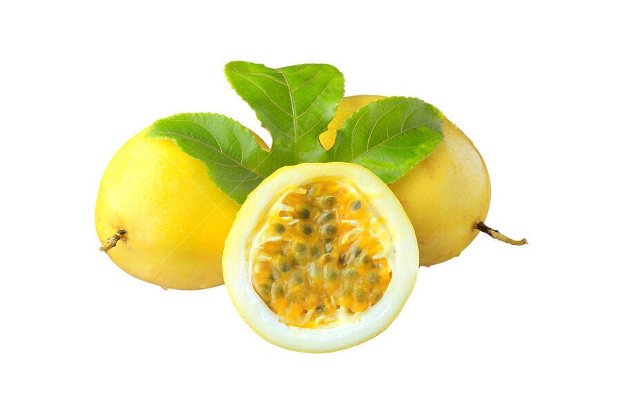Maracujá amarelo fresco cortado com folhas verdes em fundo branco