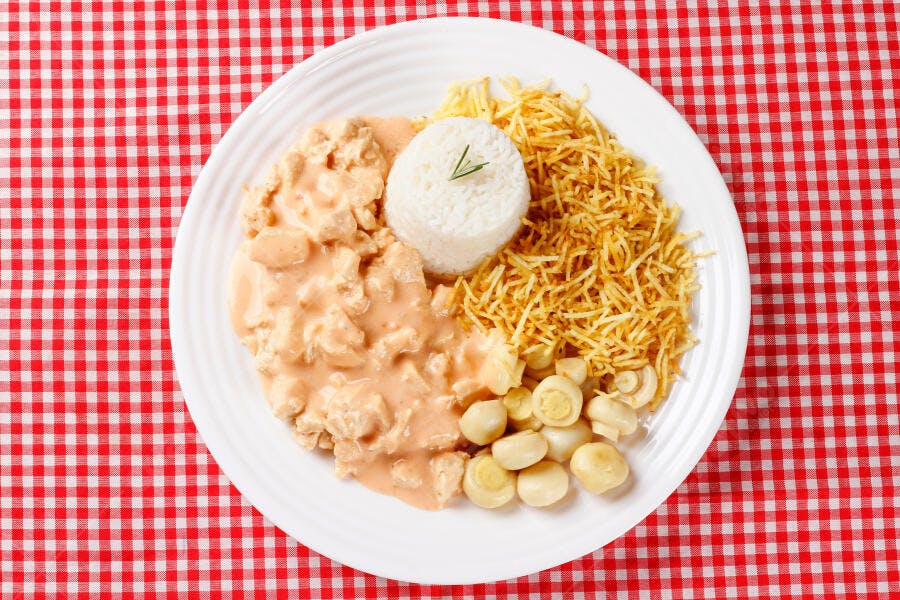 Prato de estrogonofe de frango com arroz batata palha e cogumelos em toalha xadrez