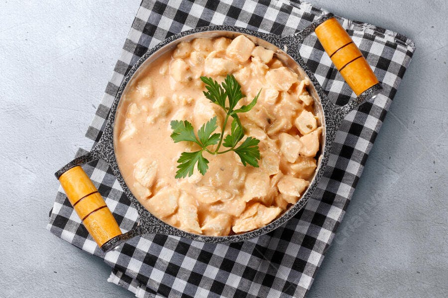 Frango cremoso com salsa em panela rústica sobre toalha xadrez