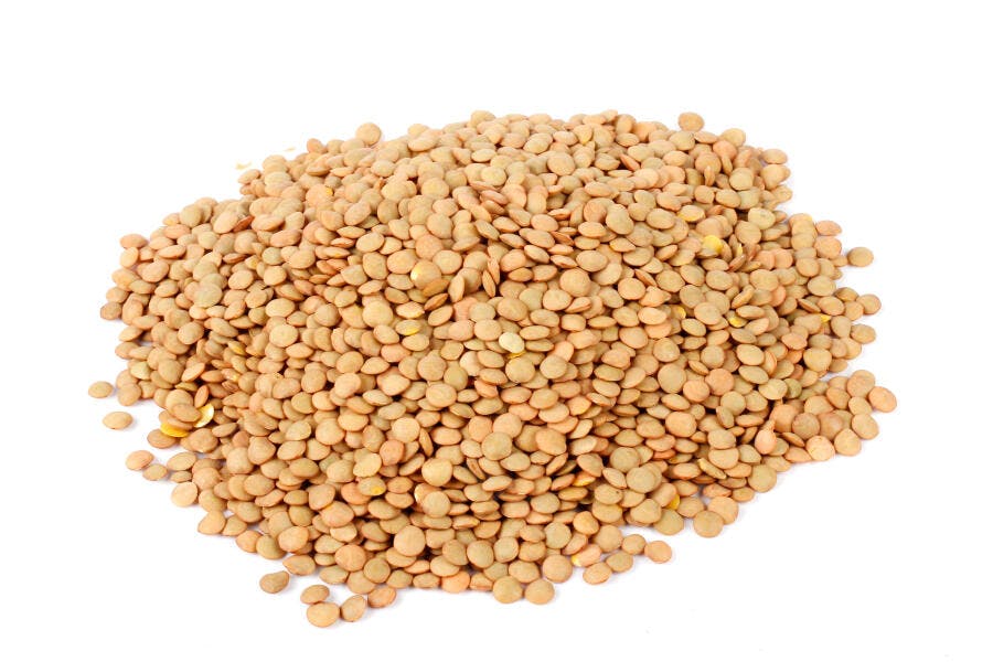 Pilha de lentilhas secas marrom claras para cozinhar em fundo branco puro