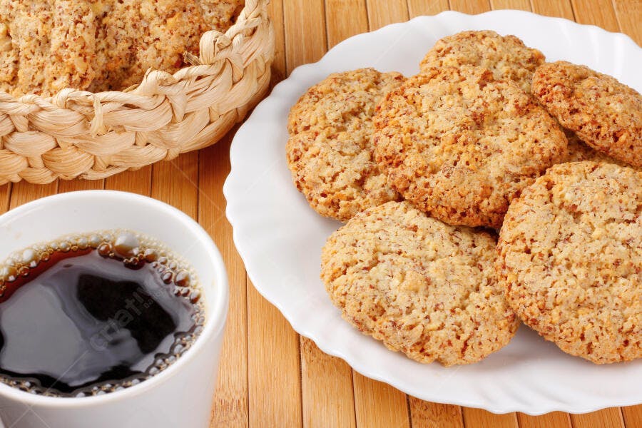 Biscoitos caseiros de aveia e nozes com café na mesa de madeira clara