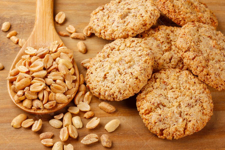 Biscoitos de amendoim e amendoins torrados na colher de pau em mesa de madeira rústica