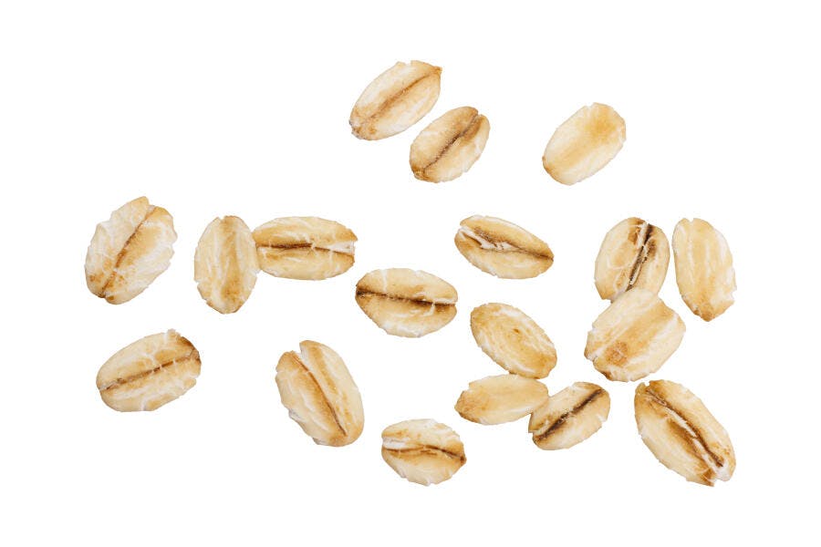 Flocos de aveia integrais soltos em fundo branco ingrediente para café da manhã