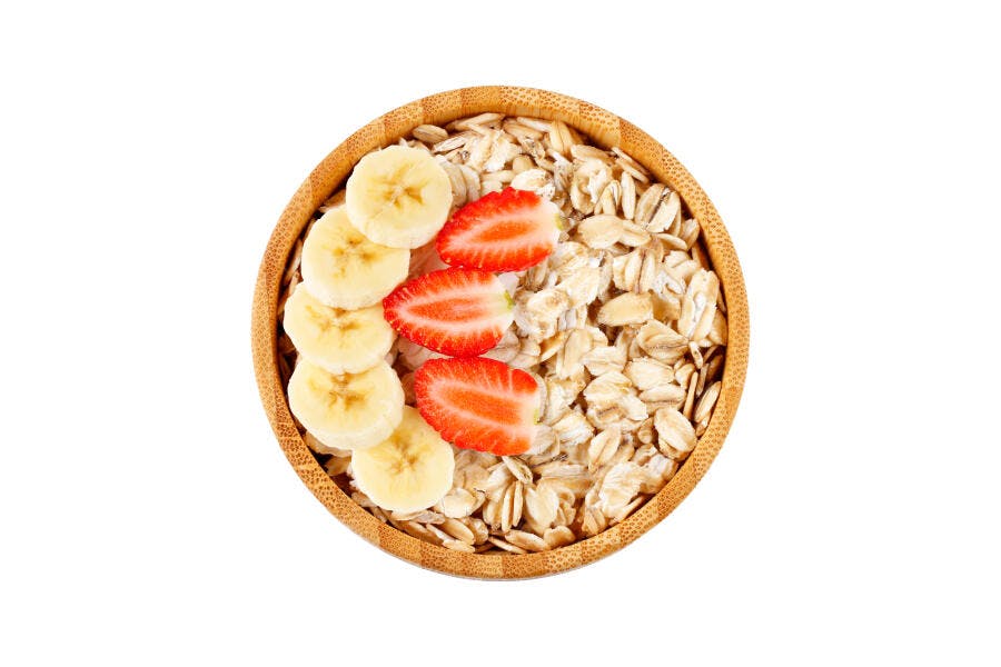 Tigela de aveia com banana e morangos frescos sobre fundo branco café da manhã saudável