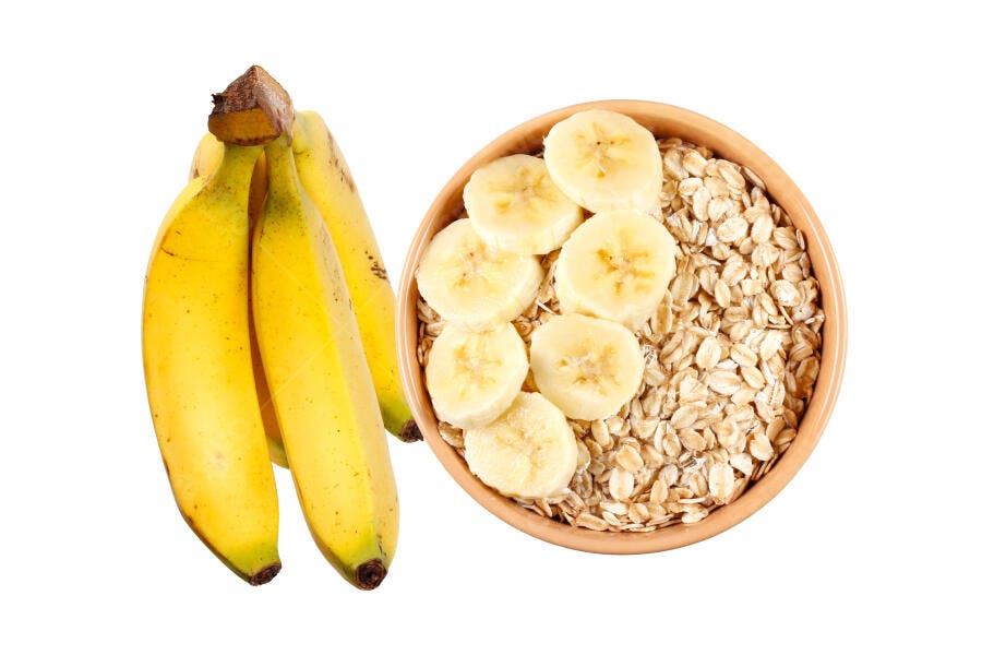Bananas amarelas maduras e aveia com fatias de banana em tigela