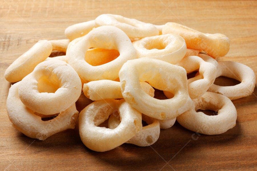 Biscoitos de polvilho crocantes brancos sobre mesa de madeira rústica