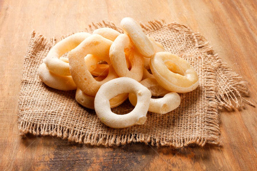 Biscoitos de polvilho crocantes em tecido de juta sobre mesa de madeira