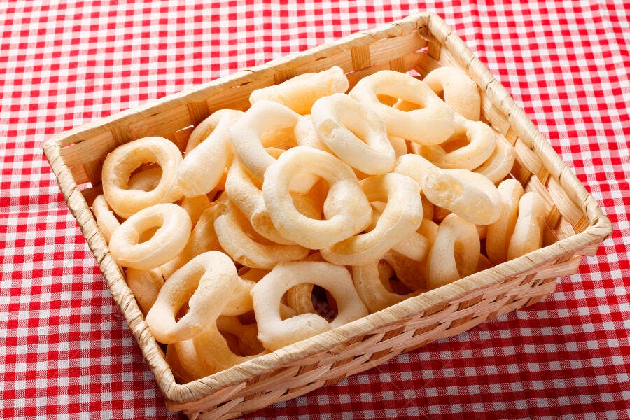 Biscoitos de polvilho tradicionais em cesta rústica sobre toalha xadrez vermelha