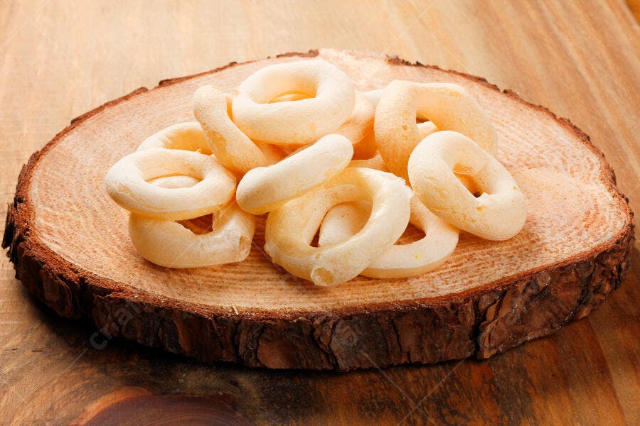 Biscoitos de polvilho brancos em fatia de tronco de madeira rústico