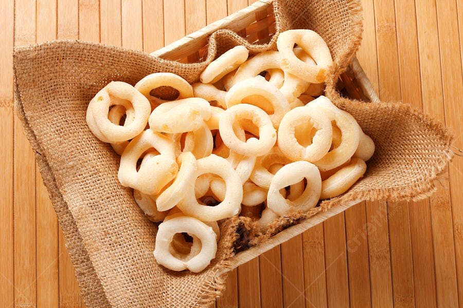 Biscoitos de polvilho crocantes em cesta rústica sobre madeira clara
