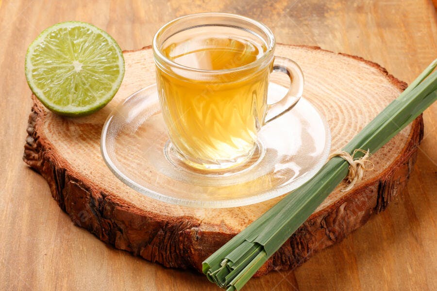 Chá de capim-limão e limão em caneca de vidro sobre tronco de madeira