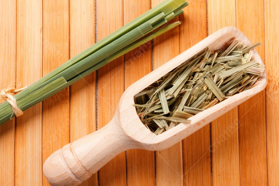 Capim-limão fresco e seco em colher de madeira sobre esteira de bambu