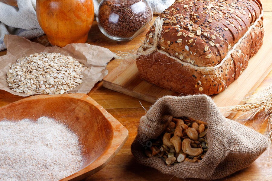 Pão integral fatiado com grãos sementes e aveia em mesa rústica de madeira