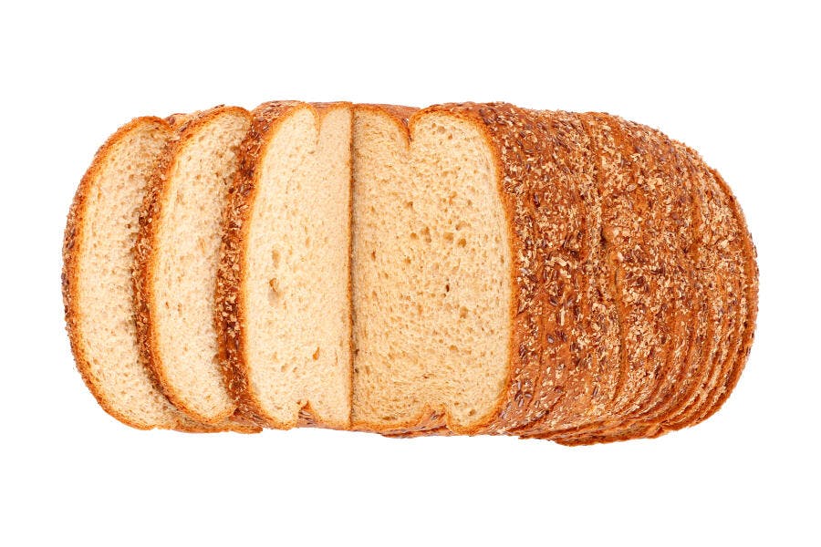 Pão integral fatiado com grãos escuros em fundo branco para café da manhã