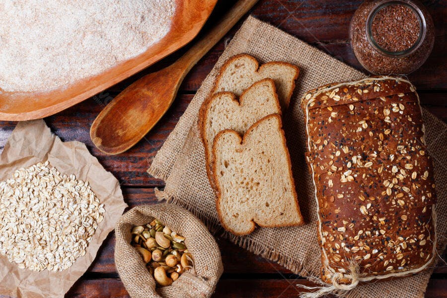 Pão integral fatiado com grãos e farinha em mesa rústica de madeira